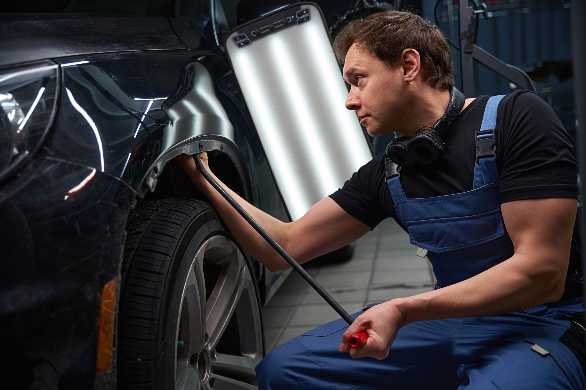 Experienced car body technician is repairing damaged automotive bodywork